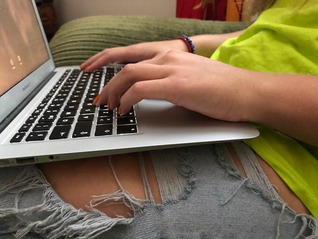 Bilden visar en laptop som någon håller i sitt knä