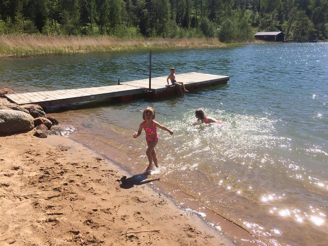 Bilden visar badande barn på en sandstrand